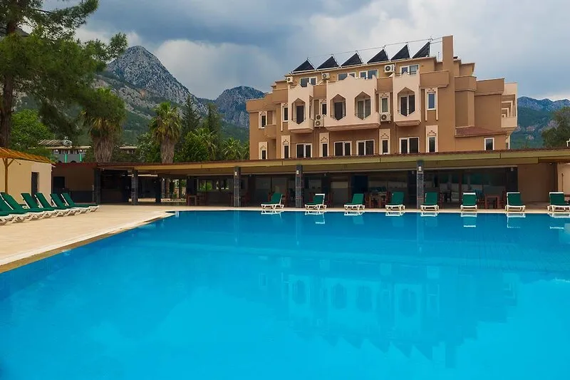 Velik zunanji bazen Alexius Beach Hotela z ležalniki in razgledom na gore.