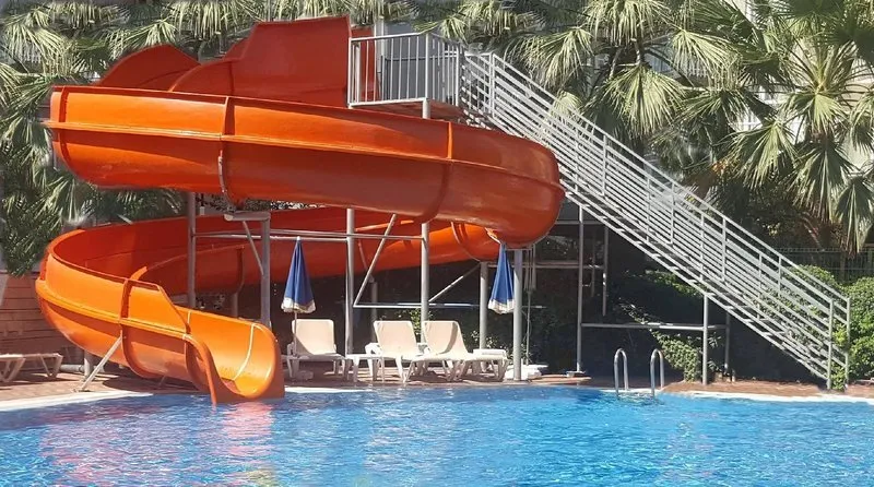 Oranžen spiralni vodni tobogan ob hotelskem bazenu