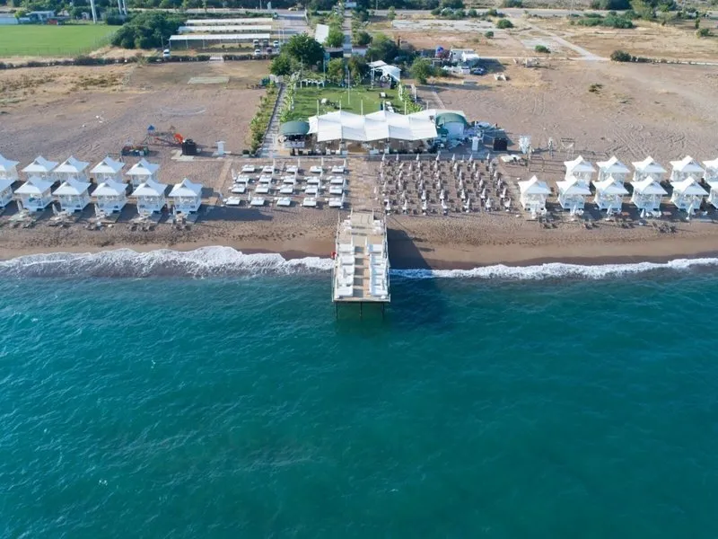 Pogled iz zraka na plažni klub s pomolom in belimi gazebami