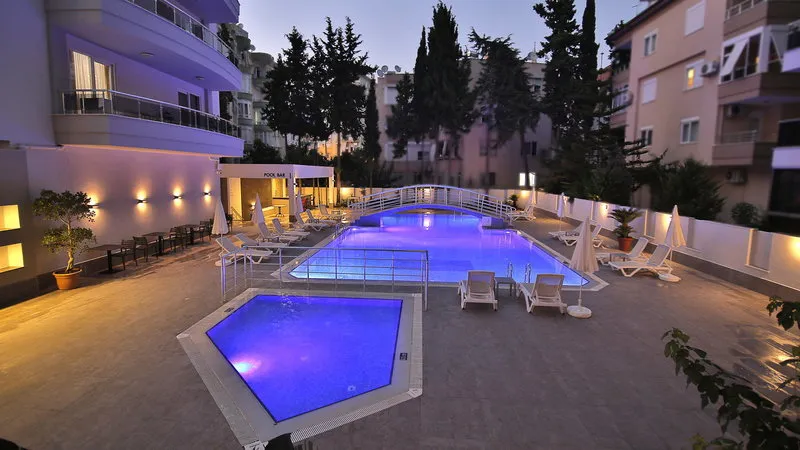 Osvetljen zunanji bazen hotela Ramira Joy ob večeru.